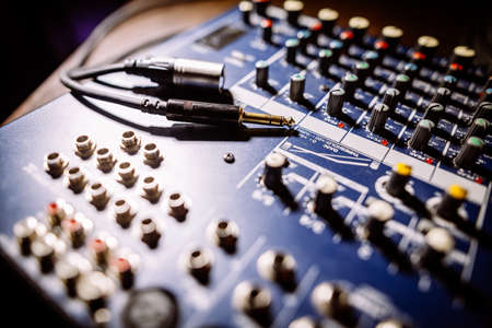 Close up shot of a mixer desk with many buttons and cables.