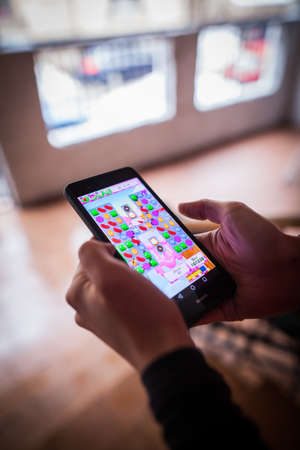 BUCHAREST, ROMANIA - January 25, 2017: Close up shot of a person's hands, holding a smartphone and playing Candy Crush Saga game.のeditorial素材