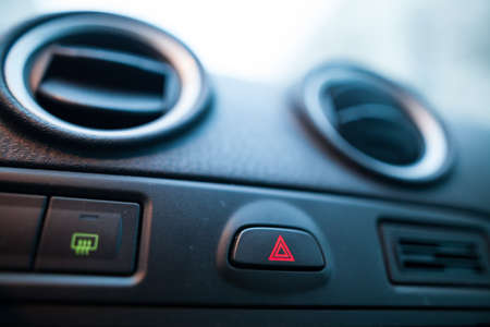 Color close up shot of a car's hazard button on dashboard.
