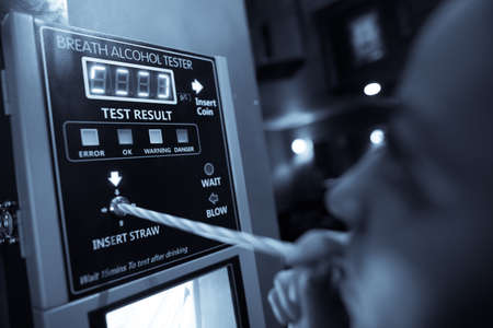 Close up shot of an alcohol tester on a wall, and a person blowing through a straw.の写真素材