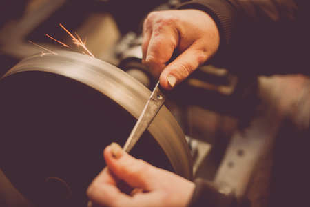 Close up shot of a man's hands sharpening a scissors.