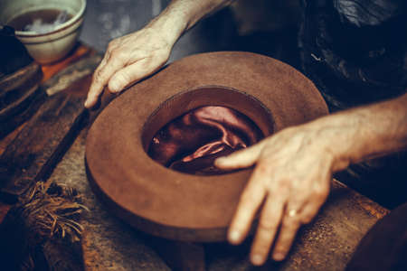 Close up shot of a hatter's hands, manufacturing a hat.