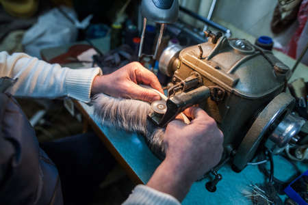 Color image of a tailor using a fur sewing machine.