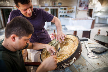 Bukhara, Uzbekistan - June 4, 2017: Artisans carve into metal plates in the historical city of Bukhara, Uzbekistan.のeditorial素材
