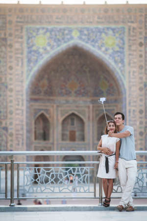 Samarkand, Uzbekistan - June 5, 2017: A couple takes a selfie in front of the Registan palace, Samarkand, Uzbekistan.のeditorial素材