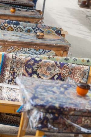 Row of tables covered with traditional carpets in a restaurant in Iran.の写真素材