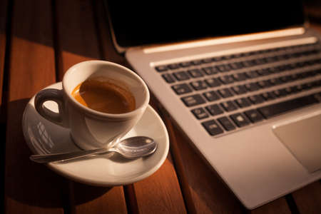 Color image of a coffee cup and a laptop keyboard on a wooden table, from above.の写真素材