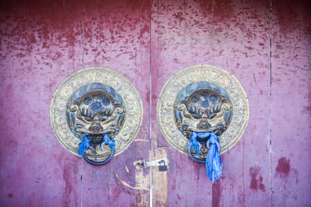 Entrance to a Buddhist temple, with scarves and lion heads.