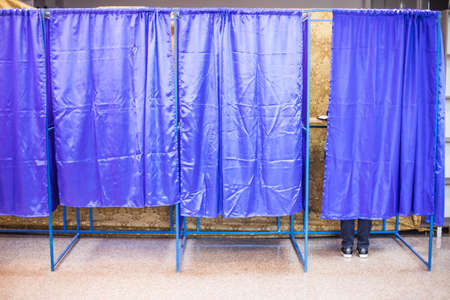 Color image of an unidentifiable person voting in booths at a polling station, during elections.の写真素材
