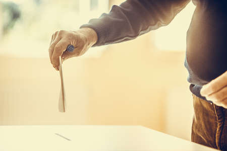 Color image of a person casting a ballot at a polling station, during elections.の写真素材