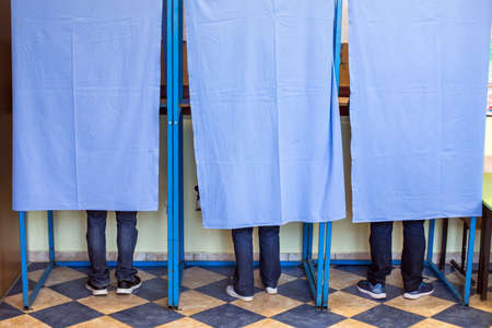 Color image of unidentifiable persons voting in booths at a polling station, during elections.の写真素材