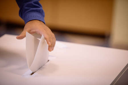 Color image of a person casting a ballot at a polling station, during elections.の写真素材