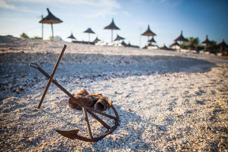 Horizontal shot of a rusty anchor on a sandy beach.の写真素材