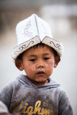 Murghab, Tajikistan - June 21, 2017: A child walks down a street, wearing a traditional hat, in Murghab, Tajikistan.のeditorial素材