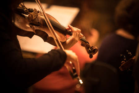 Close up shot of a woman performing on a violin during a concert.