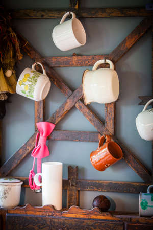 Various cups hanging in a rustic kitchen.の写真素材