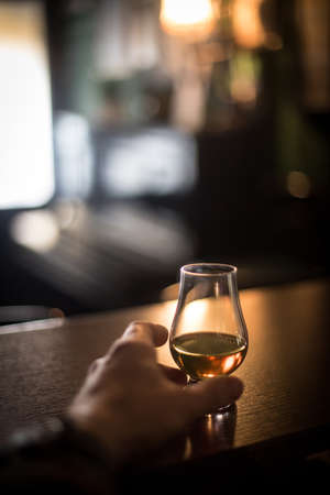 Close up shot of a hand grabbing a Glencairn whisky glass.