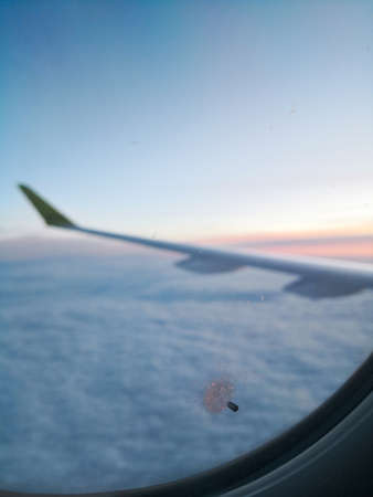 Color close up shot of a little hole in the window of a passenger airplane, flying above the clouds.の写真素材