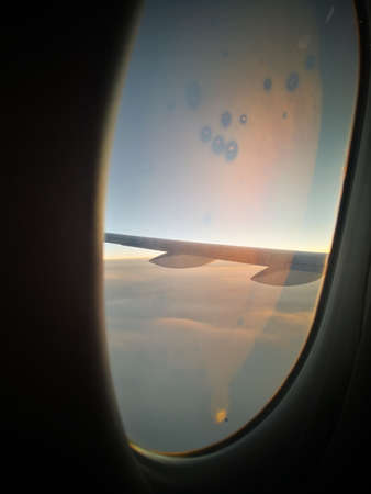 Color close up shot of a little hole in the window of a passenger airplane, flying above the clouds.の写真素材