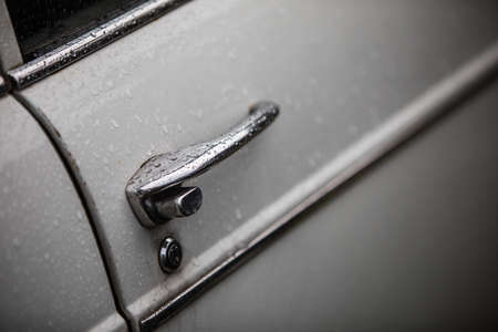 Close up shot of a vintage car door handle with rain drops.の写真素材