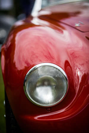 Close up vertical image of the headlight of a red vintage classic car.の写真素材