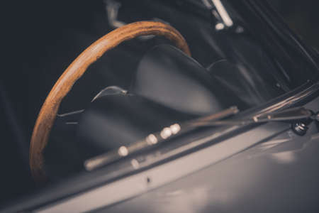 Color close up of the wooden steering wheel of an old classic car.