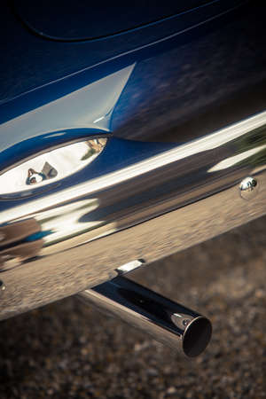 Close up vertical shot of a blue car exhaust pipe.