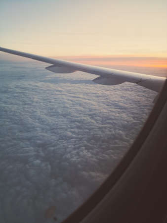 Color close up shot of the window of a passenger airplane, flying above the clouds.