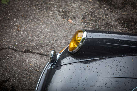 High angle image of the wet hood and headlight of a blue vintage classic car.