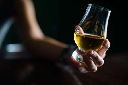 Close up shot of a hand grabbing a Glencairn whisky glass.の写真素材