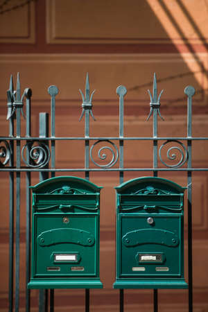 Two vintage green mail boxes on a fence.の写真素材