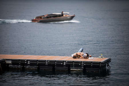 Vardenna, Italy - May 25, 2019: A couple is kissing on a pier on the lake Como, in Vardenna, Italy.のeditorial素材
