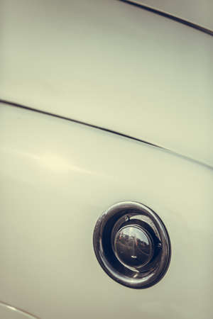 Close up shot of a fuel cap on a white vintage car.