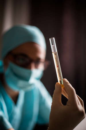 Conceptual photograph of a doctor's hands holding and looking at a test tube while with positive...