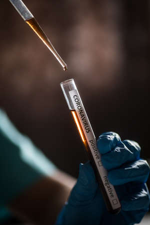 Conceptual photograph of a doctor taking samples from a test tube with a pipette, while testing for...