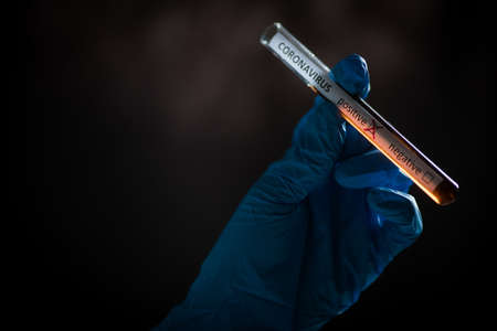 Conceptual photograph of a doctor's hands holding and looking at a test tube while with positive...