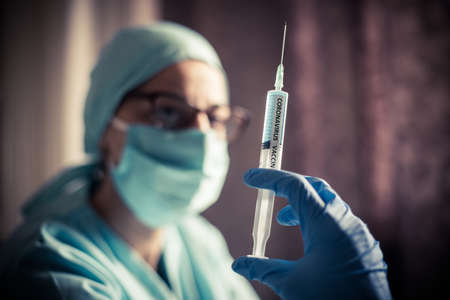Conceptual image of a nurse holding a syringe with the coronavirus COVID-19 vaccine.の写真素材