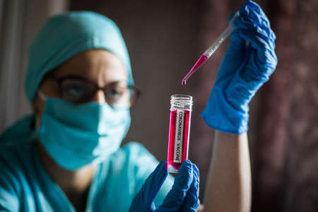 Conceptual image of a nurse using a pipette and a recipient with the coronavirus COVID-19 vaccine.