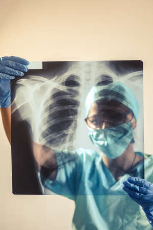 Conceptual image of a doctor holding and analyzing an x-ray of some lungs.の写真素材