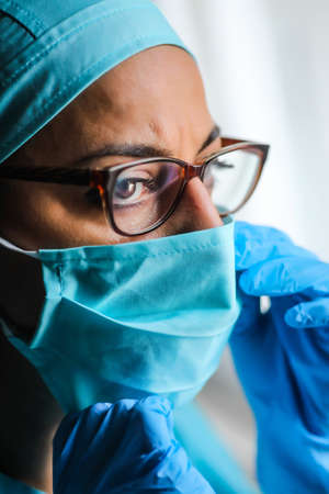 Close up shot of a woman doctor adjusting her surgical mask and glasses, in natural light.の写真素材