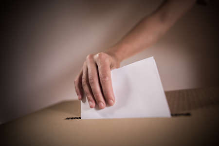 Conceptual image of a person voting, casting a ballot at a polling station, during elections.