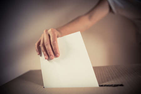 Conceptual image of a person voting, casting a ballot at a polling station, during elections.の写真素材