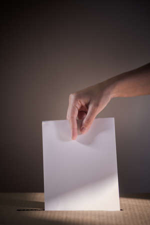 Conceptual image of a person voting, casting a ballot at a polling station, during elections.の写真素材