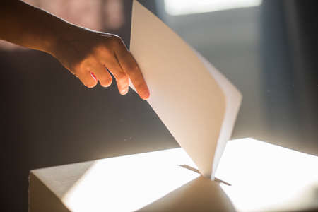 Conceptual image of a person voting, casting a ballot at a polling station, during elections.の写真素材