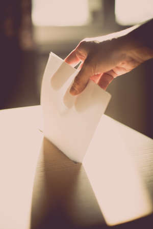Conceptual image of a person voting, casting a ballot at a polling station, during elections.の写真素材