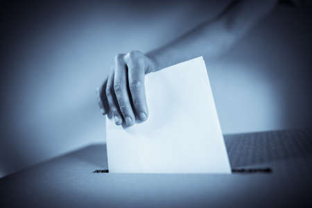 Conceptual image of a person voting, casting a ballot at a polling station, during elections.の写真素材
