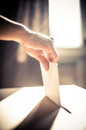 Conceptual image of a person voting, casting a ballot at a polling station, during elections.の写真素材