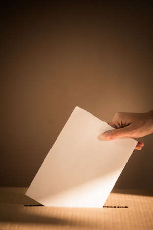 Conceptual image of a person voting, casting a ballot at a polling station, during elections.の写真素材