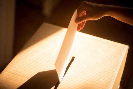 Conceptual image of a person voting, casting a ballot at a polling station, during elections.