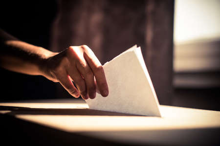 Conceptual image of a person voting, casting a ballot at a polling station, during elections.